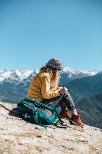 Frau schreibt ein Reisetagebuch in den Bergen und bekommt so den Kopf frei, um besser zu schlafen. Bildrechte: Tyler Nix via Unsplash